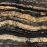 Layers of shale exposed on coastline.
