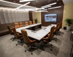 Modern conference room in Abu Dhabi with a U-shaped marble table, ergonomic chairs, LED lights, and a large display screen.
