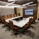 Modern conference room in Abu Dhabi with a U-shaped marble table, ergonomic chairs, LED lights, and a large display screen.