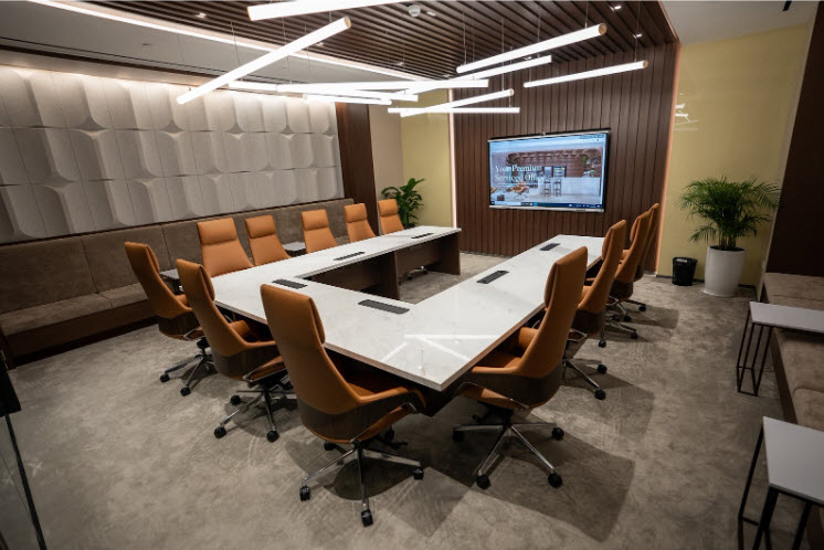 Modern conference room in Abu Dhabi with a U-shaped marble table, ergonomic chairs, LED lights, and a large display screen.